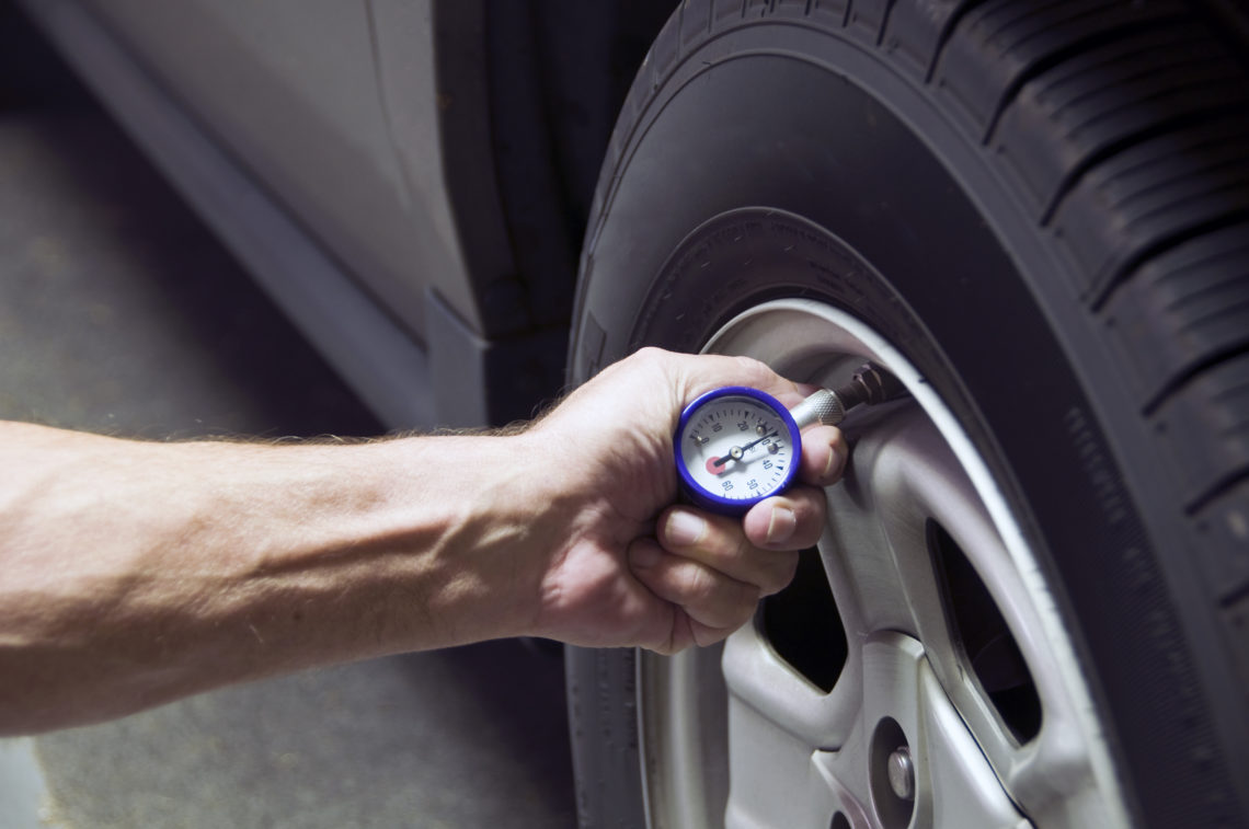 Mechanic checking tire pressure for increased gas milage